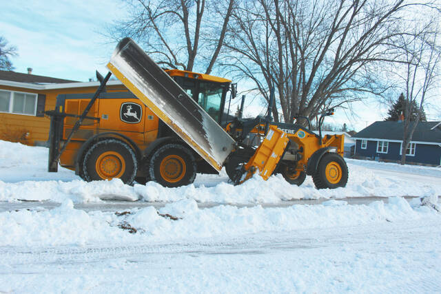 First, a grader cuts down the ice and snow that have accumulated on each side of the citys streets and avenues bringing it into the center of the roadway. (photos by Louise Oleson, DLJ Editor)