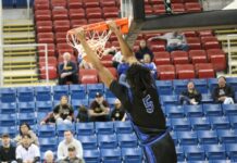 Indians bounce back from quarterfinal disappointment to beat Turtle Mountain
Marial Deng hangs off the rim as he completes a dunk during Four Winds/Minnewaukans consolation semifinal game against Turtle Mountain at the Fargodome. (Photo by Mojo Hill)