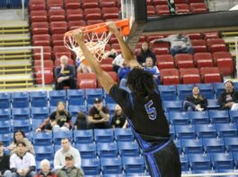 
			
				                                Marial Deng hangs off the rim as he completes a dunk during Four Winds/Minnewaukans consolation semifinal game against Turtle Mountain at the Fargodome. (Photo by Mojo Hill)
 
			
		