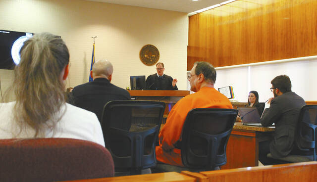 Werner Kunkel, center in orange, with his defence team to his left, Northeast District Court Judge Theodore Sandberg on the bench, and Ramsey County States Attorney Daniel Howell on Kunkels right.
