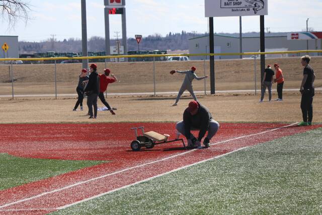 Assistant coach Parker Schmid puts first base into the ground.
                                 Photo by Mojo Hill