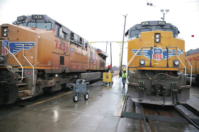 A Union Pacific worker walks between two locomotives that are being serviced in a railyard in Council Bluffs, Iowa, on Dec. 15, 2023.
                                 AP Photo/Josh Funk, File