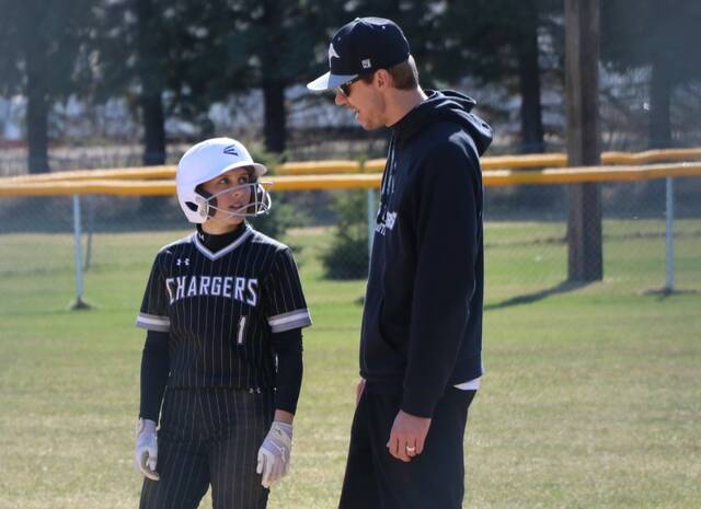 Rylee Flaagan chats with assistant coach Gus Kueber after reaching first base.
                                 Photo by Mojo Hill