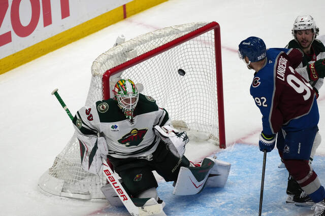 Minnesota Wild goaltender Jesper Wallstedt, left, allows a goal by Colorado Avalanche center Nathan MacKinnon as left wing Gabriel Landeskog looks on in the third period of Game 5 of an NHL Stanley Cup hockey second-round playoff series, Wednesday, May 13, 2026, in Denver.
                                 AP Photo/David Zalubowski