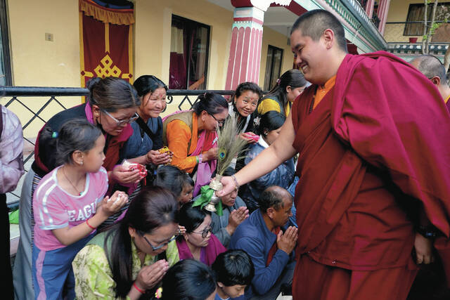 U.S.-born Buddhist lama Jalue Dorje smiles as he blesses people by tapping bowed heads with a ritual vase and a peacock feather at the end of 12 days of empowerments, or initiation rituals and teachings, bestowed by the abbot of Shechen Monastery in Kathmandu, Nepal, on Sunday, April 12, 2026.
                                 AP Photo/Luis Andres Henao