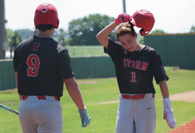 Max Palmer catches his breath, removing his helmet while Hunter Remmick waits to bat.