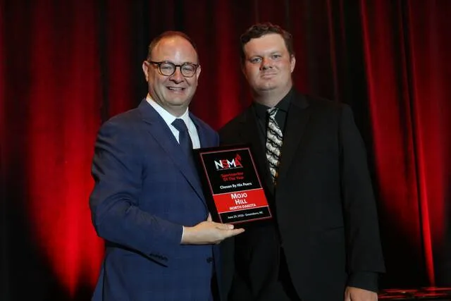 Recently-retired NBA insider Adrian Wojnarowski (left) poses with the 2025 NSMA North Dakota Sportswriter of the Year, Mojo Hill (right).
                                 Photo courtesy of Daniel Coston, NSMA