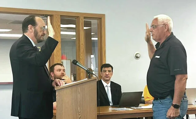Judge Peter Halbach administers the Oath of Office to Commissioner Rob Hach for another term.
                                 Photo by Mark C. Robinson