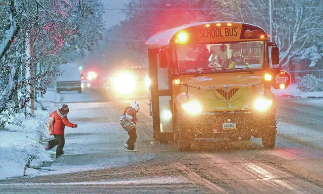 Kids board a school bus on Rosser Avenue in east Bismarck during snowy conditions on Oct. 20, 2020. Bismarck Public Schools buses around 5,500 students each day, according to the most recent data.
                                 Photo by Tom Stromme, Bismarck Tribune