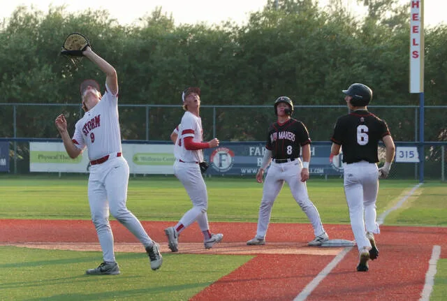 First baseman Hunter Remmick reaches his glove out to catch a popup while Cayden McCarthy watches from behind.