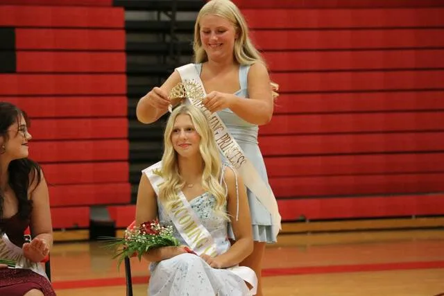 Homecoming princess Ashtyn Mertens places the queen crown on Tylie Brodinas head.