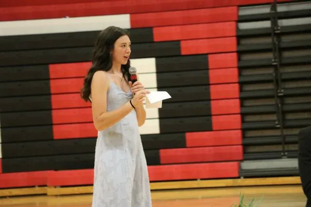Devils Lake student Chassidy Rodacker stands in front of the crowd and leads the ceremony.