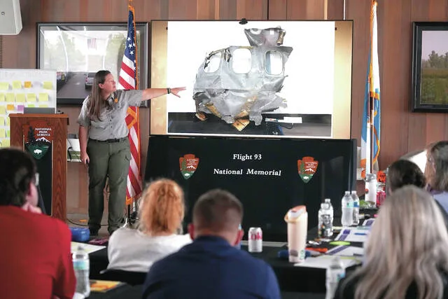 U.S. Park Ranger Betsy Keene, curator of National Parks of Western Pennsylvania, explains a slide showing a damaged part of United Flight 93 during an educators seminar at the Flight 93 National Memorial in Shanksville, Pa., Tuesday, June 23, 2026.
                                 AP Photo/Gene J. Puskar