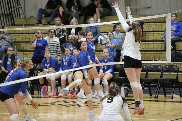 Benson County hits the ball against the net while Nelson County middle hitter Sydney Anderson leaps up in anticipation of blocking it.
Photo by Mojo Hill