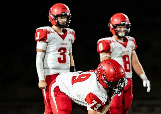 Devils Lake lineman Brenner Wayman gets set while quarterback Talan Gregory (left) and tight end Billy Enget (right) stand behind him.
                                 Photo by Cameron Carlson